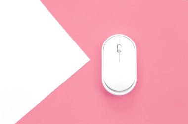Computer mouse on a pink background close-up, top view, conceptual minimalism.