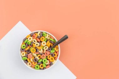 Colored breakfast cereal in a bowl on a colored background, flat lay, childrens healthy breakfast, copy space.