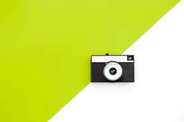 Old film camera on a green and white background, creative retro design, trendy vintage accessories, minimal flat lay, copy space.