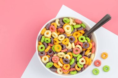 Colored breakfast cereal in a bowl on a pink background, flat lay, childrens healthy breakfast, close up.