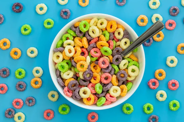 Colored breakfast cereal in a bowl on a blue background, flat lay, childrens healthy breakfast, close up.