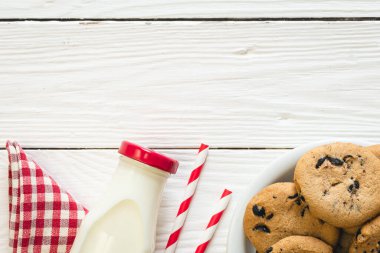 Bottle of milk, chocolate chip cookies on a wooden background, top view, copy space.