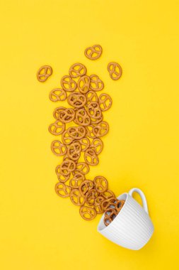 A cup with effuse pretzels on yellow background, flat lay, conceptual minimalism.