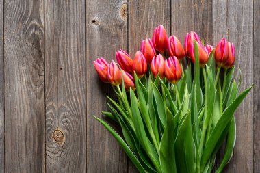 Bouquet of fresh pink tulips on a wooden background, top view, concept of mothers day, womens day, spring background with a bouquet of flowers, rustic style.