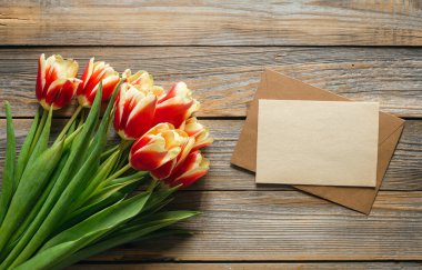 Stylish greeting card. Fresh tulips on wooden background, flat lay. Floral Greeting card template with space for text. Happy womens day. Happy Mothers day, copy space.