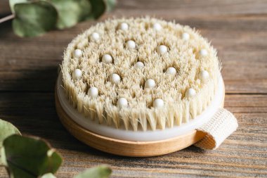 Tahta bir yüzeyde kuru masaj için bir bambu fırçasının kapağını kapatın, spa ve rahatlama araçları.