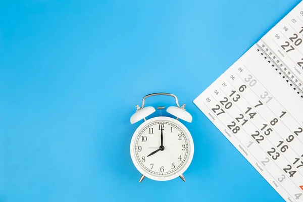 stock image Close up of calendar and alarm clock on a blue background, top view, planning for business meeting or travel planning concept, copy space.