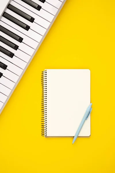 노란색 배경에 피아노와 노트북 음악적 창조성 — 스톡 사진