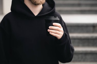 Yeniden kullanılabilir siyah bambu kabı bir adamın ellerinde, yakın plan, çevreye elverişli sıfır bambu bardağı ziyanı, plastik kavram yok.