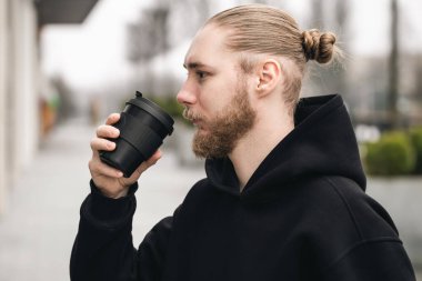 Genç, sakallı bir adam, açık havada kullanılabilen siyah bambu bardaktan içer. Yeniden kullanılabilir çevre dostu sürdürülebilir elverişli bambu kabı sıfır atık, plastik kavram yok.