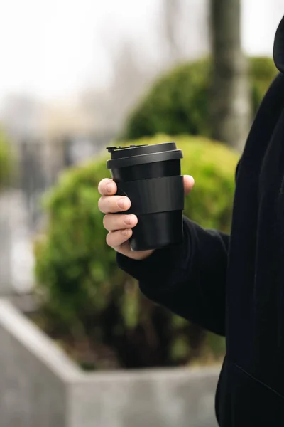 Reusable stylish bamboo black cup in the hands of a man, close-up, Eco friendly sustainable handy bamboo cup zero waste, no plastic concept.