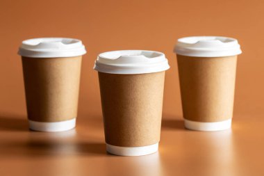 Sıfır Atık Yaşam Tarzı, Tek Kullanılabilir Kahverengi Kupa Beyaz Plastik Lid ile kahverengi arka plan izole.