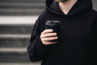 Yeniden kullanılabilir siyah bambu kabı bir adamın ellerinde, yakın plan, çevreye elverişli sıfır bambu bardağı ziyanı, plastik kavram yok.