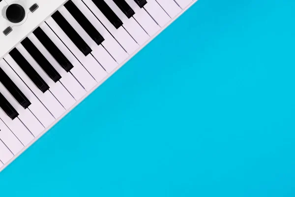 ピアノとフラットレイアウトの背景 青の背景に白いシンセサイザー 孤立した音楽キー トップビュー コピースペース — ストック写真