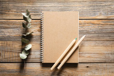 Tahta eko kalemler ve geri dönüşümlü defter. Ahşap bir arka planda, üst manzara. Çevre dostu okul kırtasiyesi.