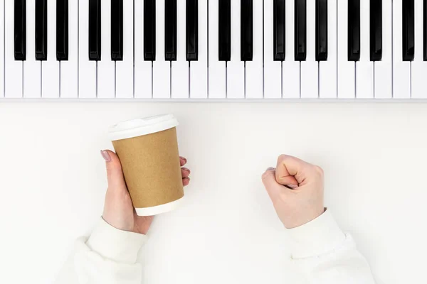 白い背景にコーヒーの紙コップとピアノを持つ女性の手 最小限の音楽的背景 音楽的創造性の概念 — ストック写真