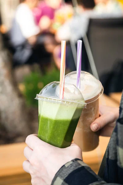 stock image Fruit smoothies in the hands of a man at a summer party, close-up. Hand holding plastic cups, health food eating lifestyle.