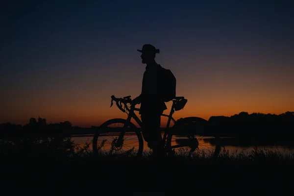 Silhueta Homem Barbudo Boné Com Uma Bicicleta Junto Lago Pôr — Fotografia de Stock