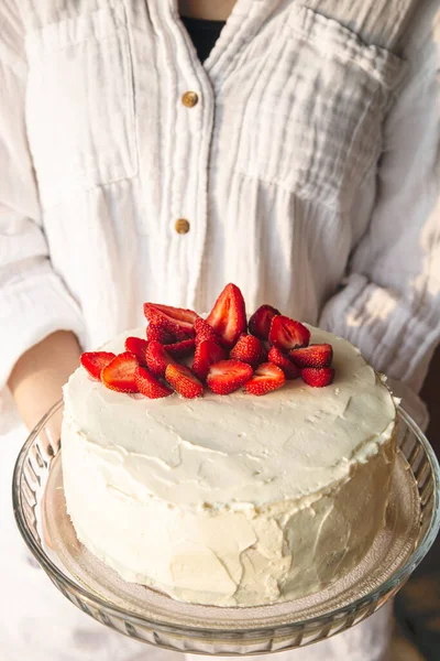 stock image Strawberry cake, decorated with fresh strawberries, in female hands, close-up.