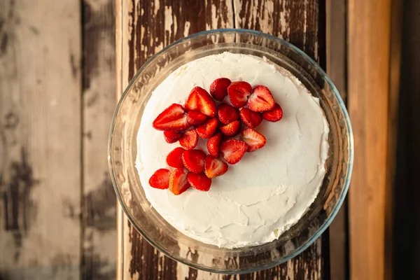 Stock image Appetizing strawberry cake decorated with fresh strawberries on a wooden background, top view.