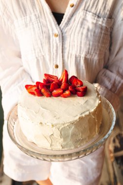 Çilekli kek, taze çileklerle süslenmiş, kadınların elinde, yakın plan..