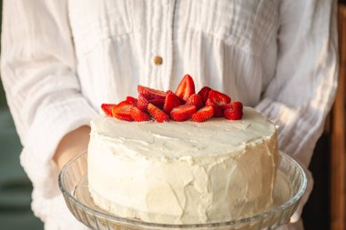Çilekli kek, taze çileklerle süslenmiş, kadınların elinde, yakın plan..