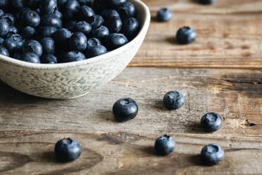 Ahşap zemin üzerinde yabanmersini olan seramik beyaz kase, köy tarzı..