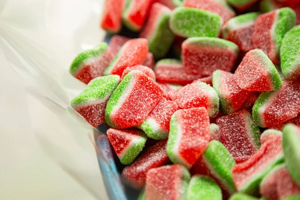 Close up of candy watermelon shape in container in candy shop, low sugar fruit gummies.
