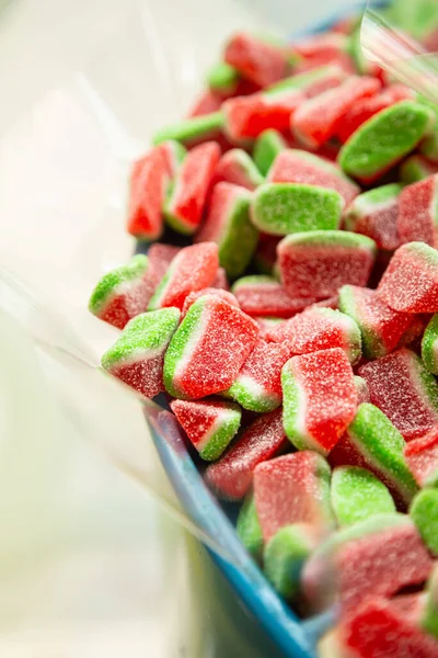 Close up of candy watermelon shape in container in candy shop, low sugar fruit gummies.