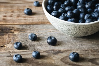 Ahşap zemin üzerinde yabanmersini olan seramik beyaz kase, köy tarzı..