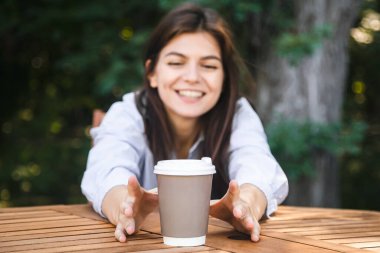 Kadınların elleri hippi kahve dükkanındaki ahşap bir masada kağıt kahve fincanına uzanıyor, kahve bağımlılığı konsepti, fotokopi alanı..