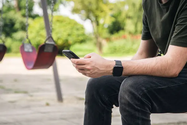 Seorang Pemuda Menggunakan Smartphone Duduk Ayunan Taman Ayah Taman Bermain — Stok Foto