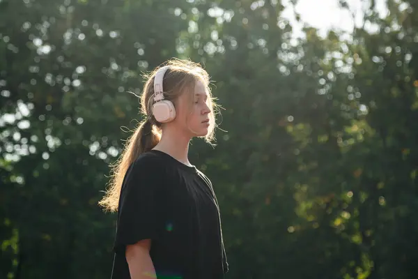 stock image Teenage girl listen music to the exercise at outdoor public stadium, copy space.