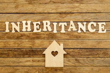 Ahşap harflerden ve ahşap bir arka planda ev modelinden yapılmış bir miras..