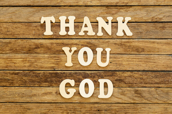 Inscription Thank you God made of wooden letters on a wooden background, top view.