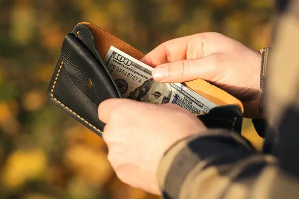 Cüzdanı erkek elinde dolar banknotları, yakın plan, turizm, seyahat ve bütçe planlama kavramı.