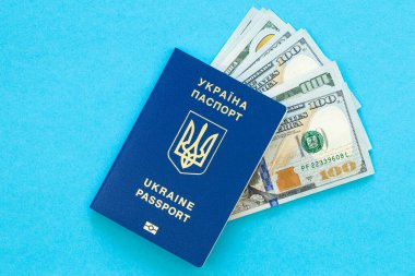 Biyometrik Ukrayna pasaportu ve mavi arka plandaki para izole edilmiş. Ukrayna vatandaşının pasaportu ve yakın plan banknotlar..