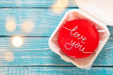 Kore usulü kırmızı bento keki. Üzerinde mavi ahşap arka plan, üst manzara, Sevgililer Günü konsepti..