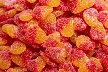 Kırmızı ve sarı jelibonların arka planında şeker kaplı kalpler var..