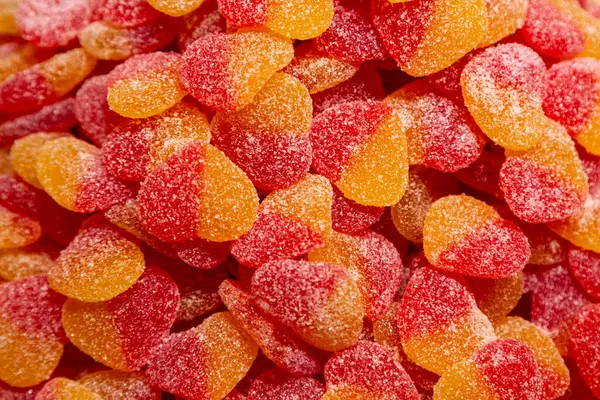 Kırmızı ve sarı jelibonların arka planında şeker kaplı kalpler var..