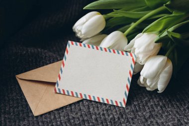 Bahar kompozisyonu, bir kartpostal ve bir buket beyaz lale, yakın plan. Boş posta kartı ve bir buket taze lale çiçeği, kopyalama alanı..