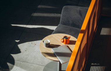 Bir dizüstü bilgisayar ve bir fincan çay, güneşli havalarda sert gölgeli bir kafenin içindeki bir masada. Uzaktan kumandalı bir kafede çalışıyorum. Serbest çalışan biri için açık alanda işyeri.