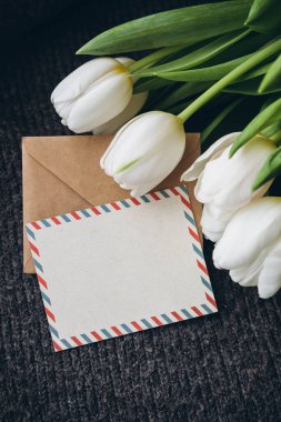 Bahar kompozisyonu, bir kartpostal ve bir buket beyaz lale, yakın plan. Boş posta kartı ve bir buket taze lale çiçeği, kopyalama alanı..