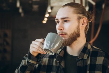 Sabahları kahve ya da çay içen sakallı çekici bir adam. Ofiste kahve molası. Boşluğu kopyala.
