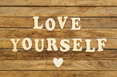 Yazıtta yazana göre, ahşap bir arka planda, ahşap harflerden yapılmış kendini sev..