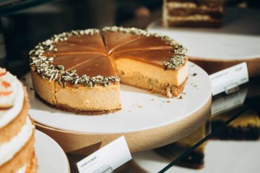 Kafe vitrininde kabak çekirdeği serpiştirilmiş balkabaklı cheesecake. Geleneksel Şükran Günü pastası.