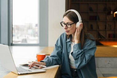 Uzaktan eğitim. Gülümseyen bir kadının portresi, dizüstü bilgisayar kullanarak, ders izleyerek, konferans ya da webinar izleyerek, çevrimiçi çalışarak. Boşluğu kopyala.