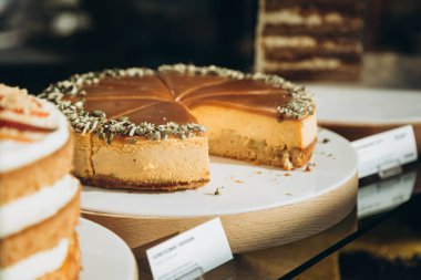 Kafe vitrininde kabak çekirdeği serpiştirilmiş balkabaklı cheesecake. Geleneksel Şükran Günü pastası.
