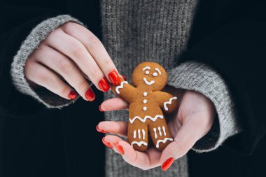 Kızıl tırnaklı bir kadının ellerinde zencefilli kurabiye adam. El yapımı zencefilli kurabiye tutan kadın elleri.