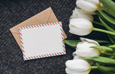Bahar kompozisyonu, bir kartpostal ve bir buket beyaz lale, yakın plan. Boş posta kartı ve bir buket taze lale çiçeği, kopyalama alanı..